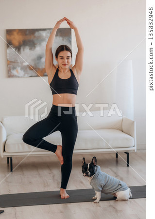 Endurance exercise. Woman with pug dog is doing yoga at home Endurance exercise. Woman with pug dog is doing yoga at home 135832948