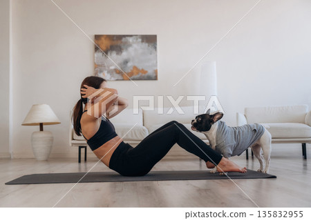 Abs exercise. Woman with pug dog is doing yoga at home 135832955