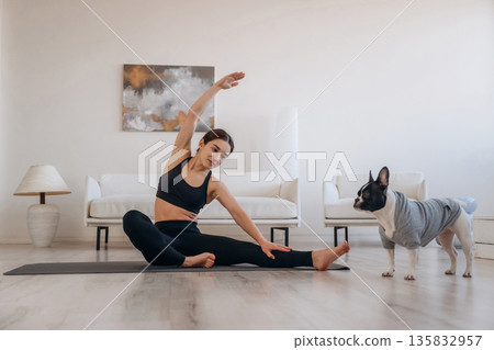 Hand up, stretching exercise. Woman with pug dog is doing yoga at home Hand up, stretching exercise. Woman with pug dog is doing yoga at home 135832957