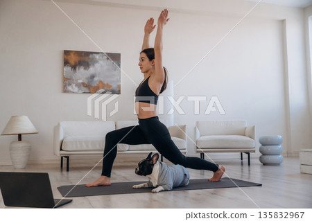 Endurance exercise. Woman with pug dog is doing yoga at home Endurance exercise. Woman with pug dog is doing yoga at home 135832967