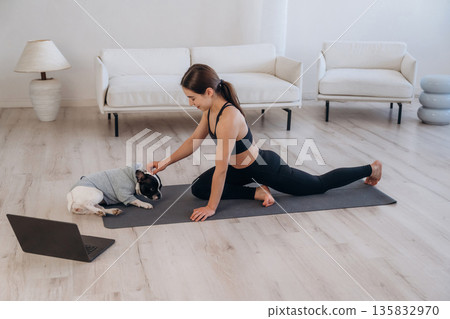Laptop is on the floor. Woman with pug dog is doing yoga at home Laptop is on the floor. Woman with pug dog is doing yoga at home 135832970