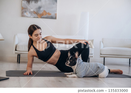 Resting on the floor. Woman with pug dog is doing yoga at home Resting on the floor. Woman with pug dog is doing yoga at home 135833000