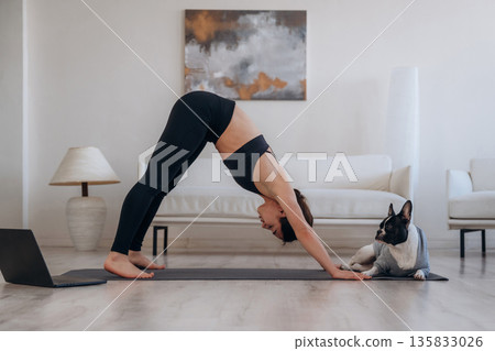 Endurance exercise. Woman with pug dog is doing yoga at home Endurance exercise. Woman with pug dog is doing yoga at home 135833026