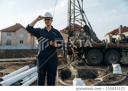 Vehicle is parked behind. Construction worker is near boring drilling machine Vehicle is parked behind. Construction worker is near boring drilling machine 135833115