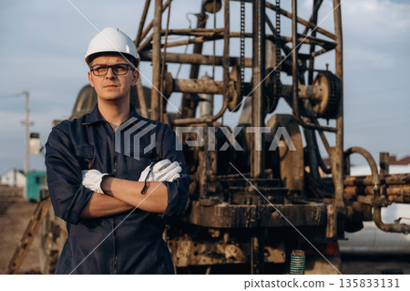 Standing with arms crossed. Construction worker is near boring drilling machine 135833131