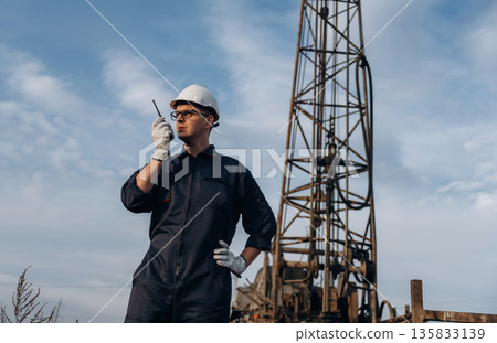 Talking by using walkie talkie. Construction worker is near boring drilling machine Talking by using walkie talkie. Construction worker is near boring drilling machine 135833139