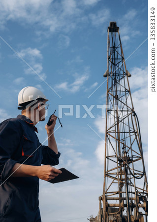 Giving orders by using walkie talkie. Construction worker is near boring drilling machine 135833149