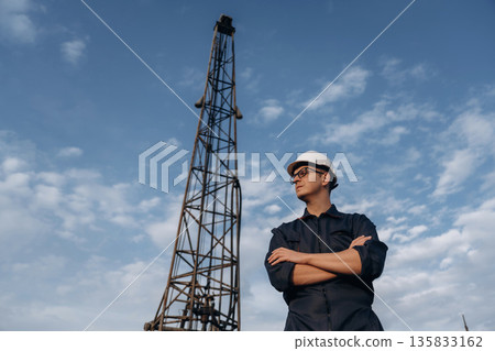 Looking to the side, arms crossed. Construction worker is near boring drilling machine Looking to the side, arms crossed. Construction worker is near boring drilling machine 135833162