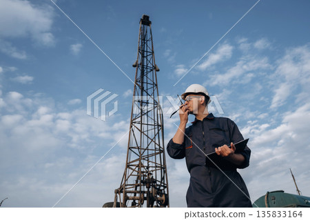 Smart guy is talking by using walkie talkie. Construction worker is near boring drilling machine Smart guy is talking by using walkie talkie. Construction worker is near boring drilling machine 135833164