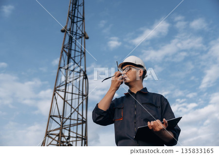 Smart guy is talking by using walkie talkie. Construction worker is near boring drilling machine Smart guy is talking by using walkie talkie. Construction worker is near boring drilling machine 135833165