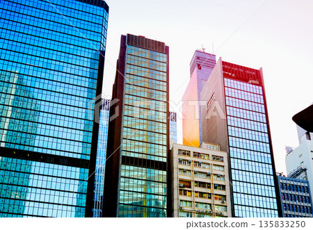 Skyscrapers tower in bright glass exteriors sunlight on sunset. Tower facade office buildings Skyscrapers tower in bright glass exteriors sunlight on sunset. Tower facade office buildings 135833250
