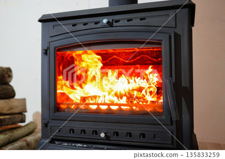Burning wood stove. Cast iron stove with burning wood inside. Wood-burning stove in room Burning wood stove. Cast iron stove with burning wood inside. Wood-burning stove in room 135833259