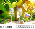 Wine glass with wine bottle of white wine on table in vineyard. Russian flag on Grape leaves 135833311