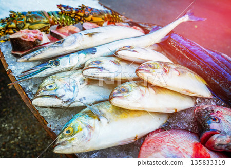 Fresh fish sale at local market in early morning. Freh seafood in ice on counter in a grocery store 135833319