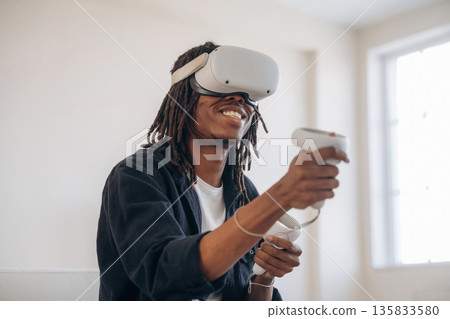 Side view, in headset. Black man in virtual reality glasses at home 135833580