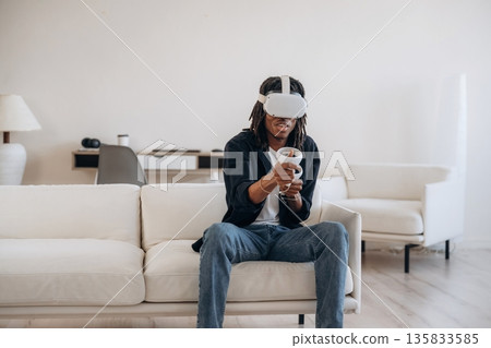 Conception of gaming. Black man in virtual reality glasses at home 135833585
