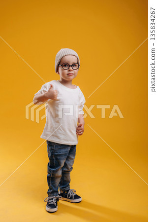 Stylish cute little boy in hat is against yellow background 135834267