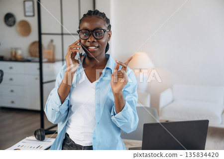 Talking by phone. Woman is at home in domestic room 135834420