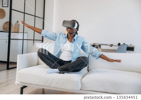 Making gestures by hands, in VR headset. Woman is at home in domestic room 135834451