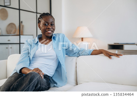 Looking forward, sitting and smiling. Woman is at home in domestic room Looking forward, sitting and smiling. Woman is at home in domestic room 135834464