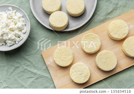 Preparing syrniki cottage cheese pancakes for breakfast on wooden board 135834518
