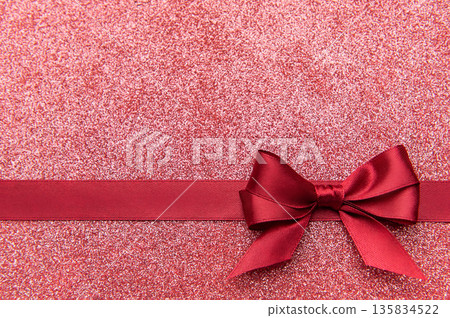 Red satin bow on glistening pink glitter background 135834522