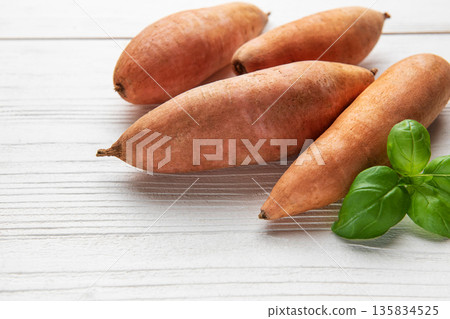Sweet potatoes and fresh basil on white wooden table 135834525