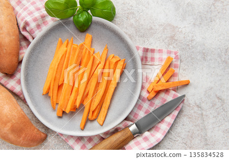 Raw sweet potato sticks on plate with basil Raw sweet potato sticks on plate with basil 135834528