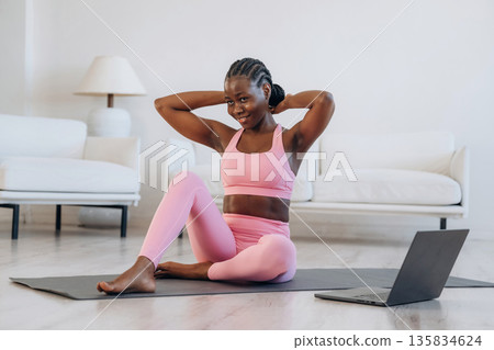On the yoga mat, sitting, laptop on floor. Woman is doing yoga at home 135834624
