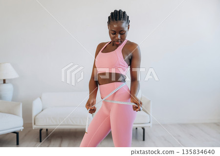 Measuring the waist, weight loss. Woman is doing yoga at home Measuring the waist, weight loss. Woman is doing yoga at home 135834640