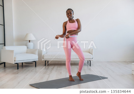 Diet conception, measuring the waist. Woman is doing yoga at home Diet conception, measuring the waist. Woman is doing yoga at home 135834644