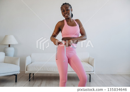 Diet conception, measuring the waist. Woman is doing yoga at home Diet conception, measuring the waist. Woman is doing yoga at home 135834646