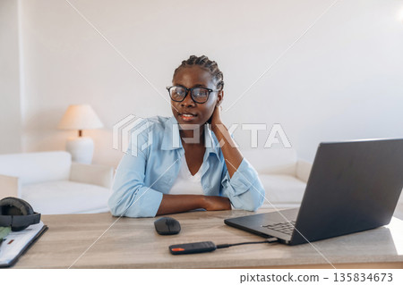 By the table with laptop. Woman is at home in domestic room By the table with laptop. Woman is at home in domestic room 135834673