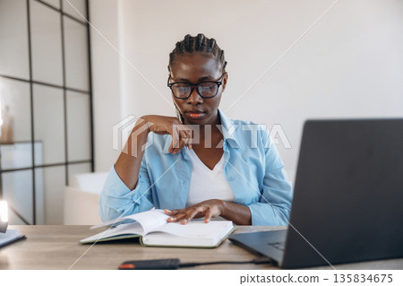 By the table with laptop. Woman is at home in domestic room 135834675