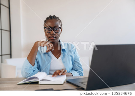 By the table with laptop. Woman is at home in domestic room 135834676