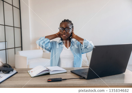 Black laptop is on the table. Woman is at home in domestic room Black laptop is on the table. Woman is at home in domestic room 135834682