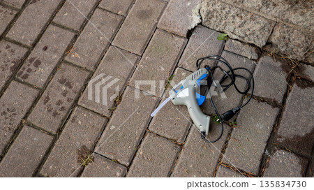 Glue gun on a paved stone surface. Craft tool for repair, construction or creative project, decorations. Crafting equipment for hobbyist. 135834730