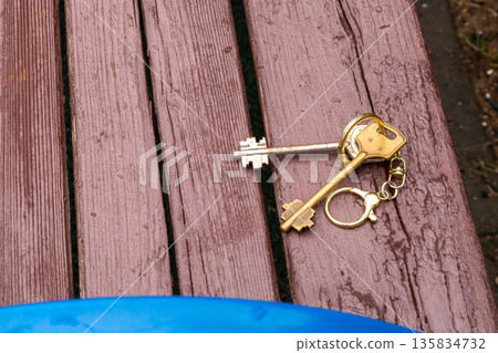 Two house keys on a wooden surface, symbolizing home ownership, mortgage, accessible housing, and purchase of property. 135834732