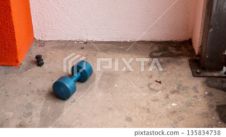 Dumbbell on a dirty concrete floor on a balcony. Concept of home workout, fitness, or neglect. Exercise equipment 135834738