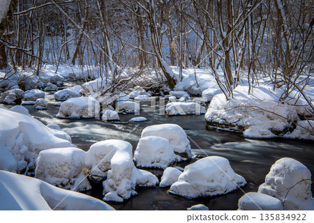 Oirase Gorge in winter: Snow caps piled up on rocks and clear stream 135834922
