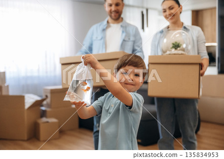 Boy is holding package with fish. Family of husband, wife and son are moving into new house 135834953