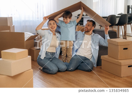 Playing with paper that is from the box. Family of husband, wife and son are moving into new house Playing with paper that is from the box. Family of husband, wife and son are moving into new house 135834985