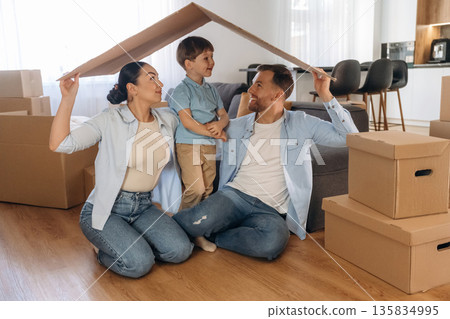 Front view, holding paper from box, sitting. Family of husband, wife and son are moving into new house 135834995