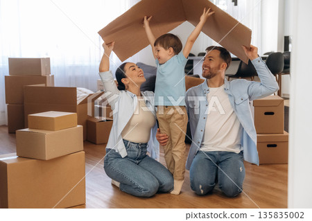 Conception of new home, under paper from box. Family of husband, wife and son are moving into new house 135835002