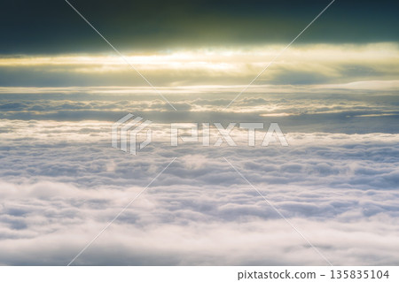 從空中俯瞰,落日餘暉映照著一片閃耀的雲海。 從空中俯瞰,落日餘暉映照著一片閃耀的雲海。 135835104