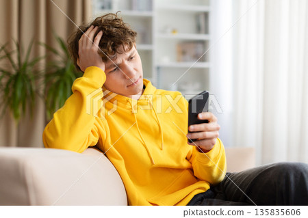Thoughtful young man checking smartphone at home, stressed or concerned 135835606