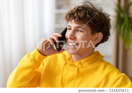 Closeup of smiling young man talking on smartphone at home Closeup of smiling young man talking on smartphone at home 135835611