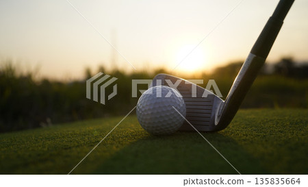 Golf clubs and balls on a green lawn in a beautiful golf course with morning sunshine. 135835664