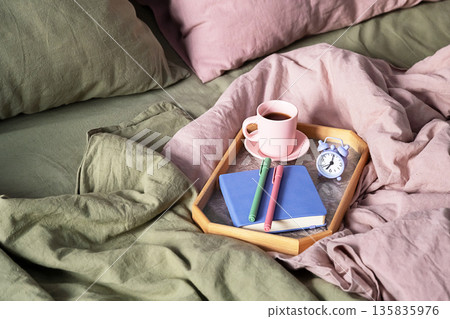 Coffee, notebook, pens, and alarm clock on bed tray. Coffee, notebook, pens, and alarm clock on bed tray. 135835976