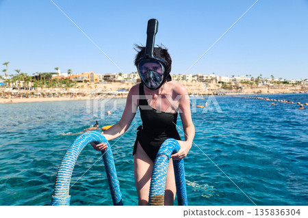 A woman overcomes her fear as she puts on a snorkel mask for the first time and dives into the water A woman overcomes her fear as she puts on a snorkel mask for the first time and dives into the water 135836304
